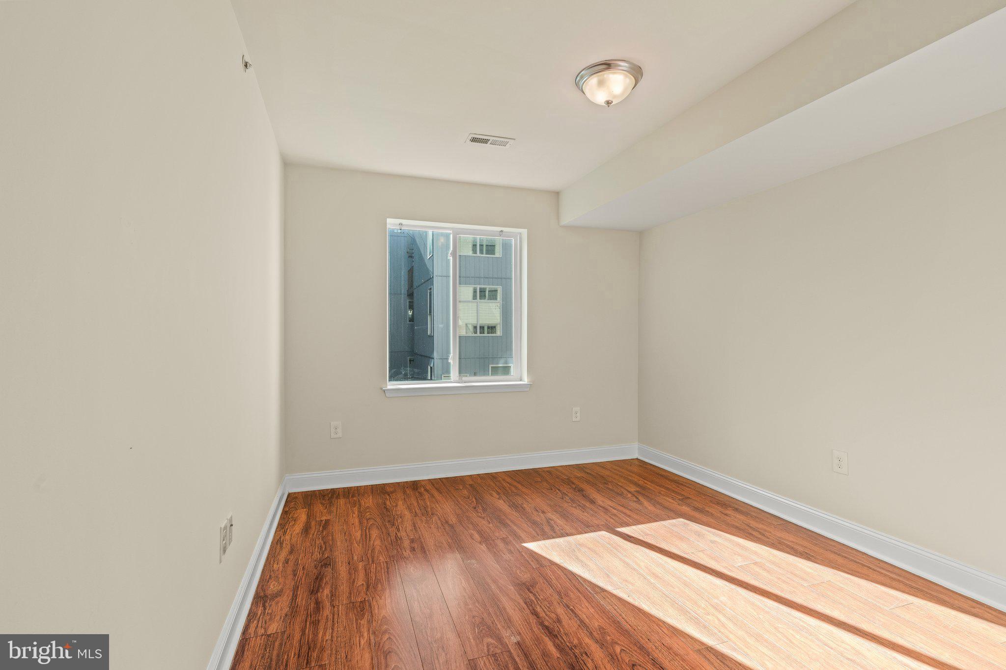1724 Master Street, Unit C Philadelphia, PA 19121 - Photo 22 of 24 an empty room with wooden floor and windows