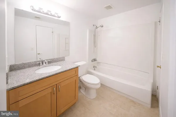 a bathroom with a granite countertop sink a toilet and shower