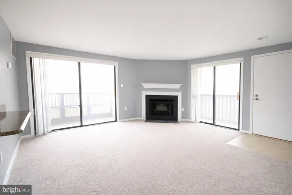 an empty room with windows and fireplace