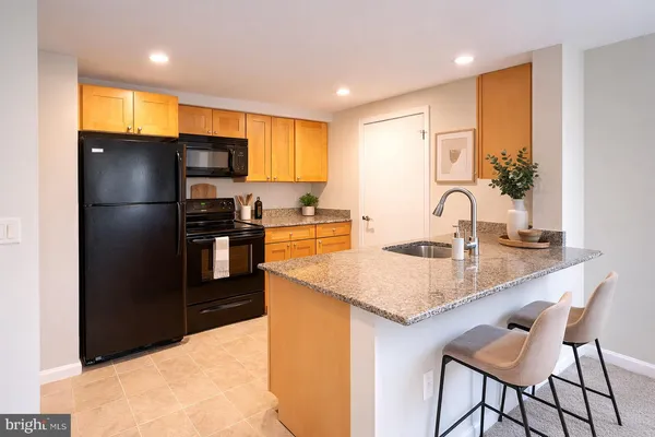 a kitchen with granite countertop a sink stainless steel appliances and refrigerator