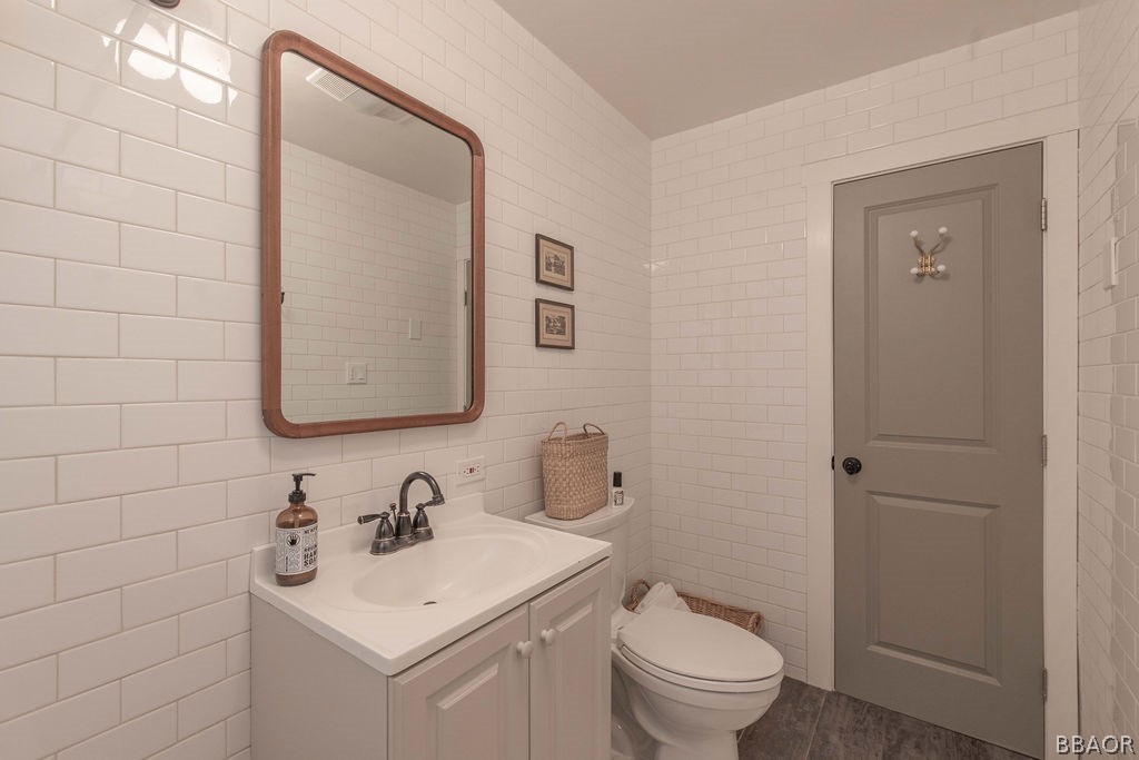 42897 Encino Road Big Bear Lake, CA 92315 - Photo 26 of 45 a bathroom with a toilet a sink a mirror and vanity
