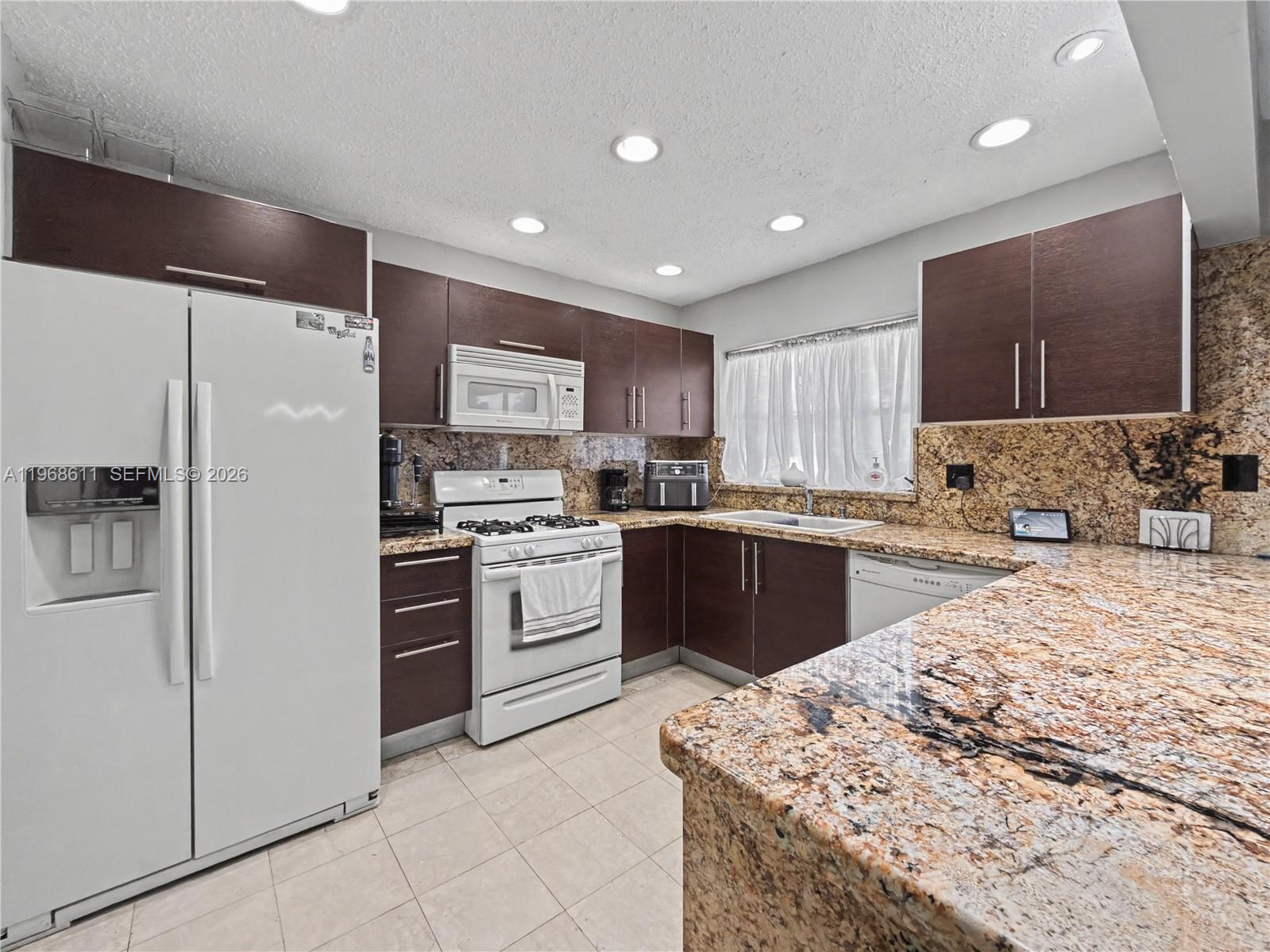 10491 Southwest 122nd Court Miami, FL 33186 - Photo 3 of 25 a kitchen with a refrigerator a sink and cabinets