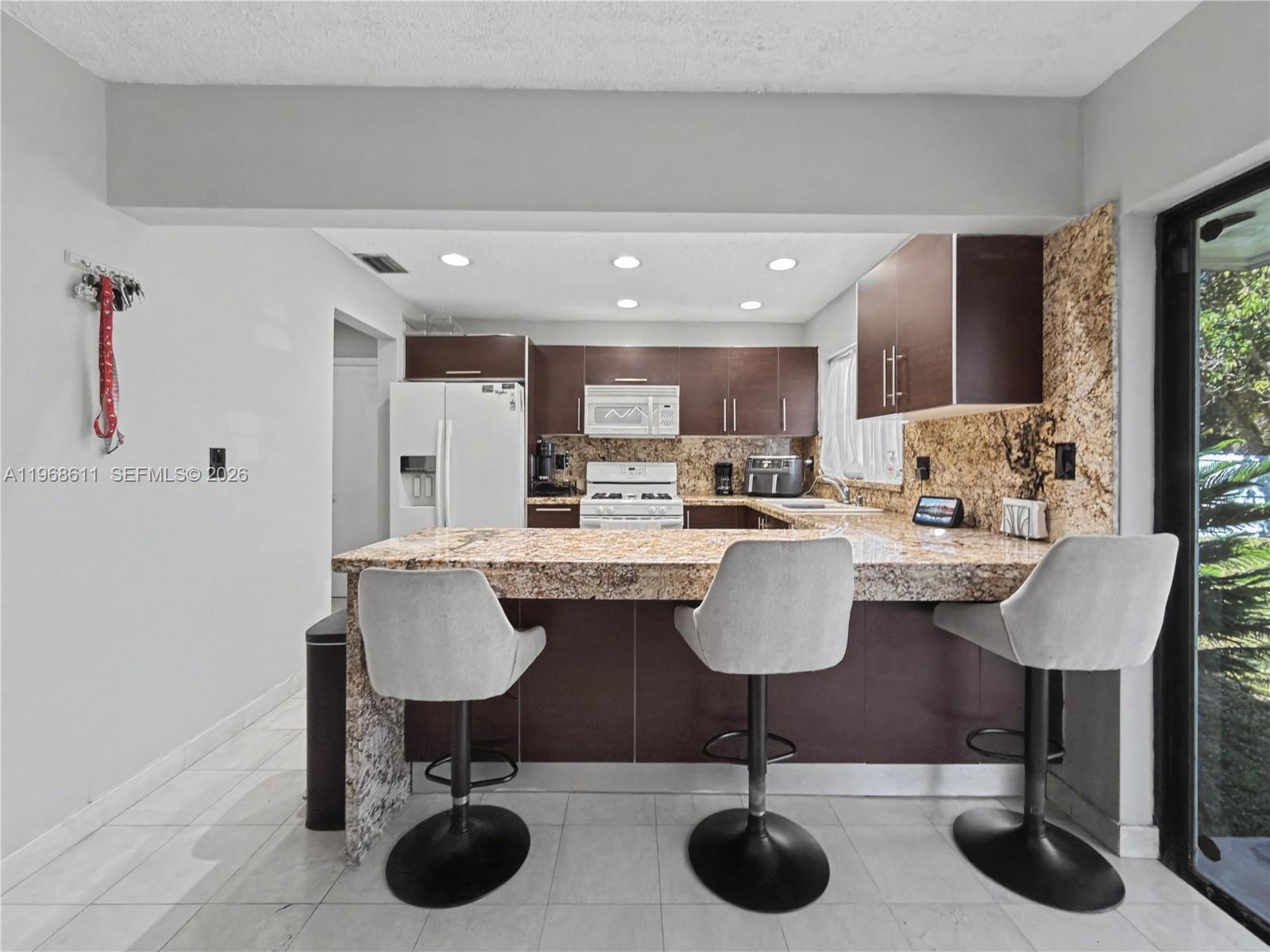 10491 Southwest 122nd Court Miami, FL 33186 - Photo 4 of 25 a kitchen with granite countertop a counter space a sink and a refrigerator