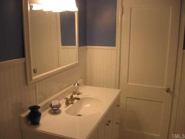 The bathroom has been updated with new vanity and fixtures. The wainscot and wood details show the integrity of the era this home was built.