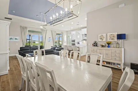 a large kitchen with stainless steel appliances kitchen island granite countertop a refrigerator a stove a sink and white cabinets with wooden floor