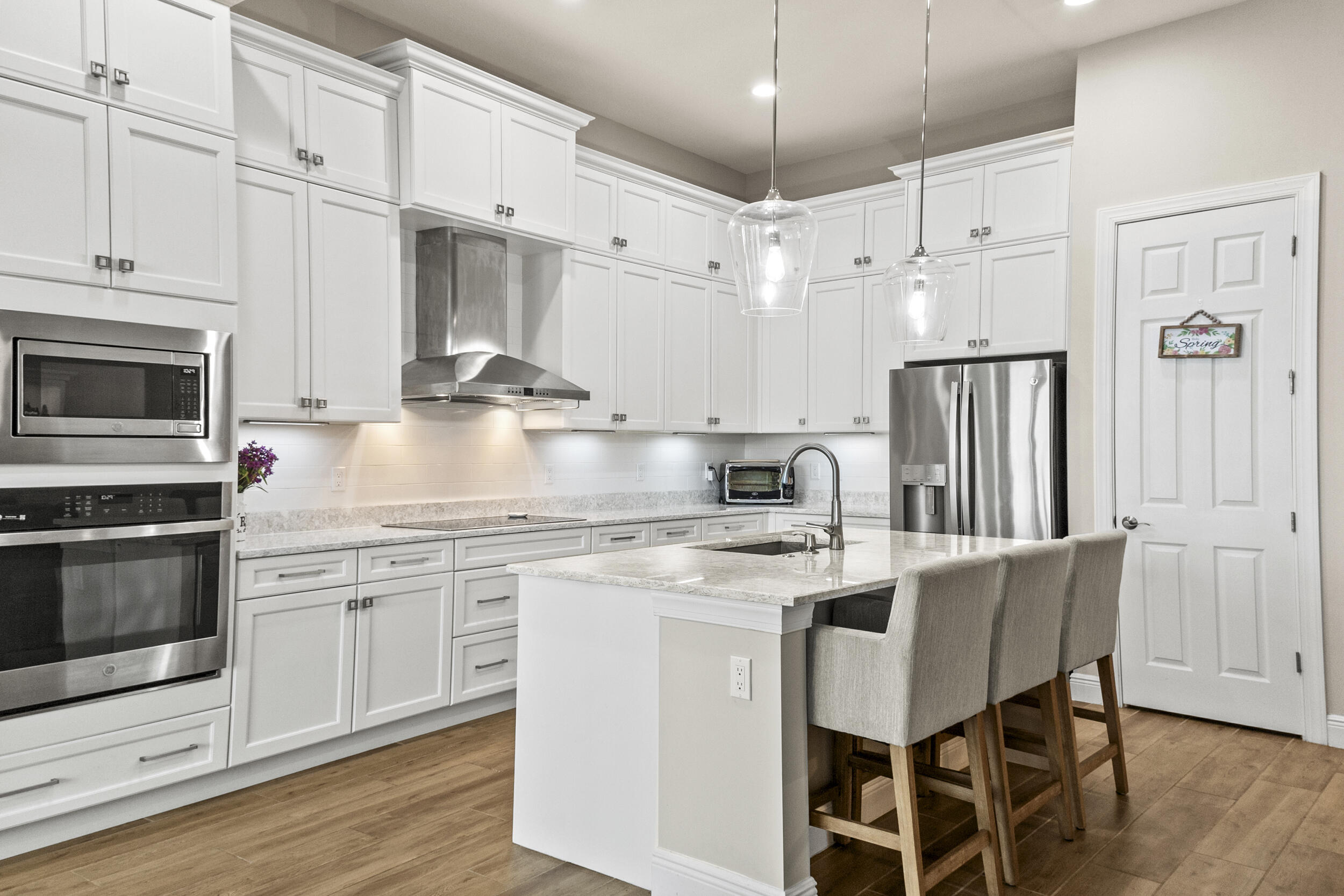 9242 Southwest Pepoli Way Port St. Lucie, FL 34987 - Photo 19 of 71 a kitchen with stainless steel appliances granite countertop a white cabinets and wooden floor