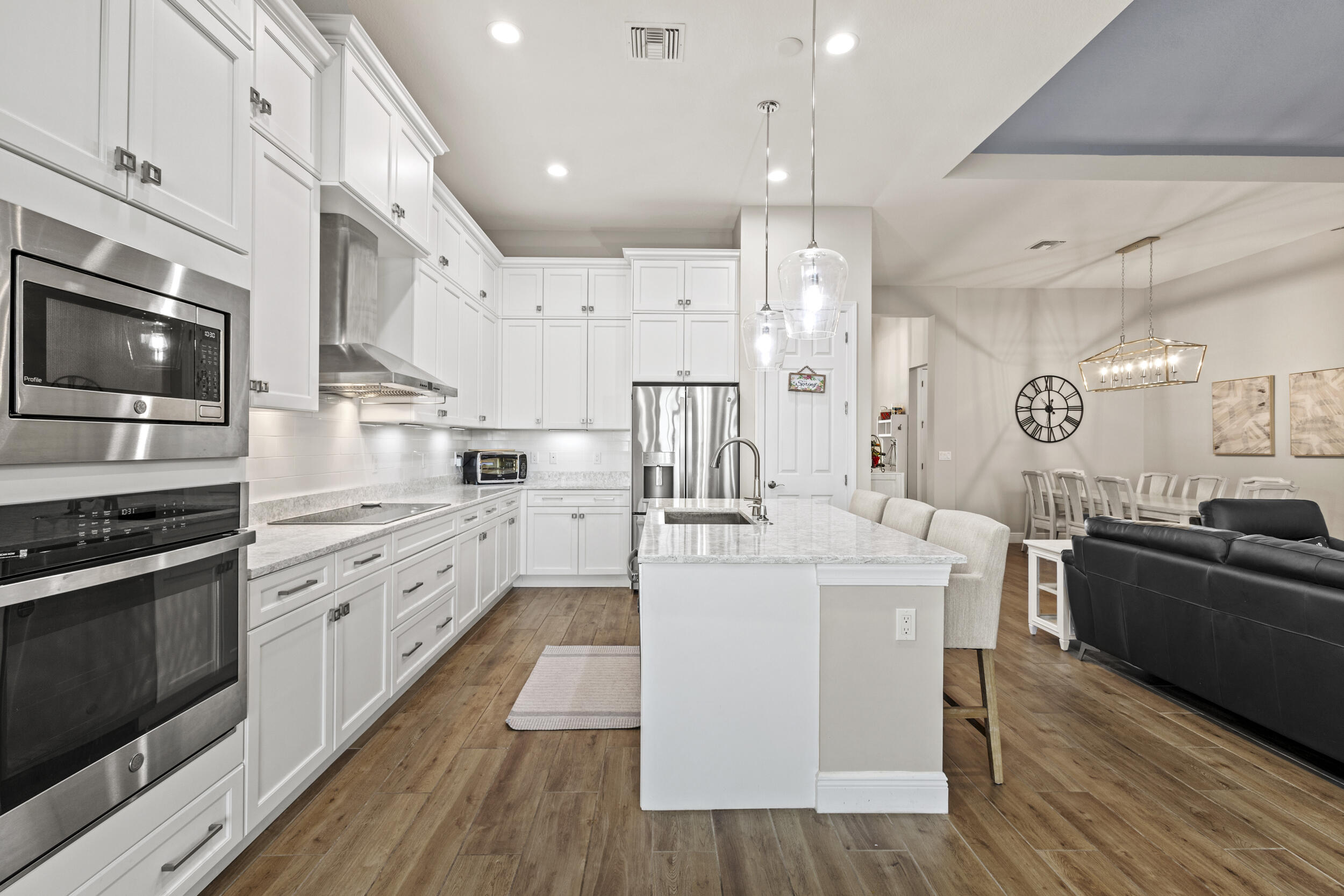 9242 Southwest Pepoli Way Port St. Lucie, FL 34987 - Photo 20 of 71 a kitchen with stainless steel appliances kitchen island granite countertop a stove top oven a sink dishwasher and a refrigerator with wooden floor