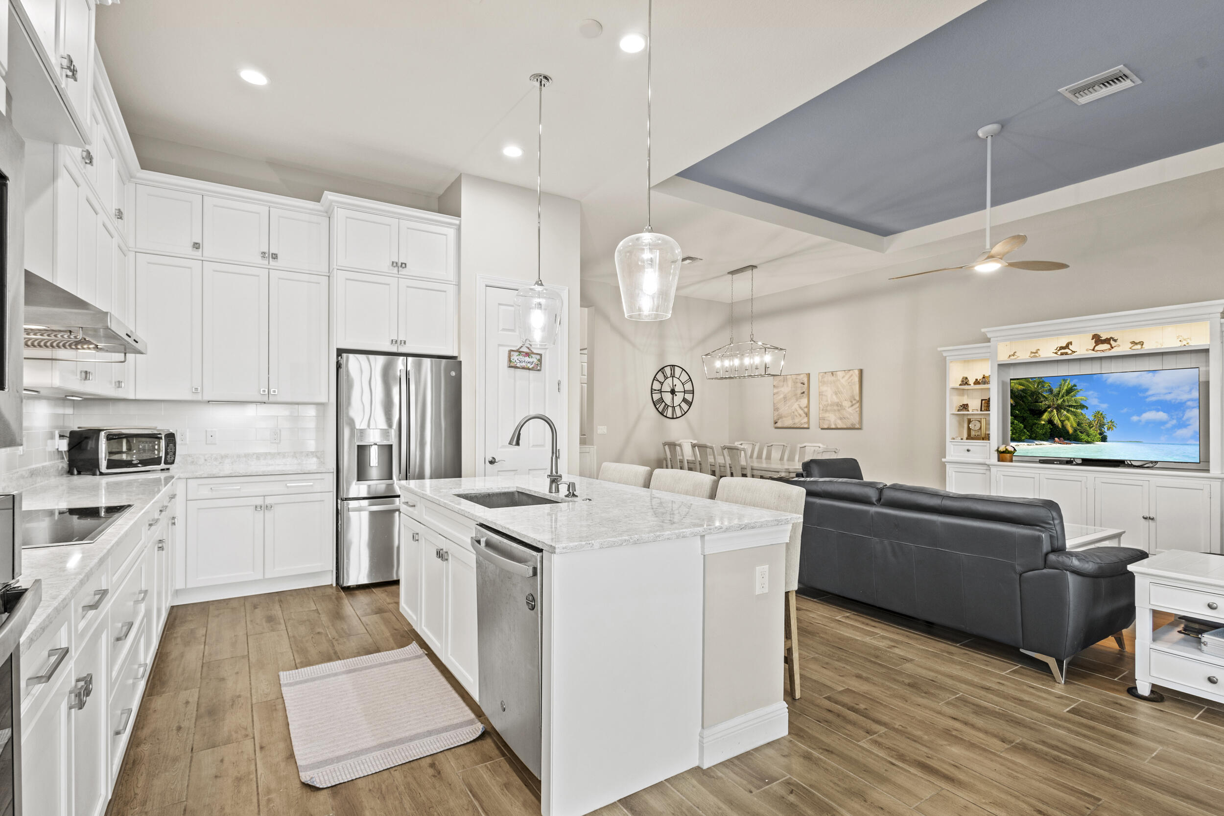 9242 Southwest Pepoli Way Port St. Lucie, FL 34987 - Photo 21 of 71 a large kitchen with stainless steel appliances kitchen island granite countertop a refrigerator a stove a sink and white cabinets with wooden floor