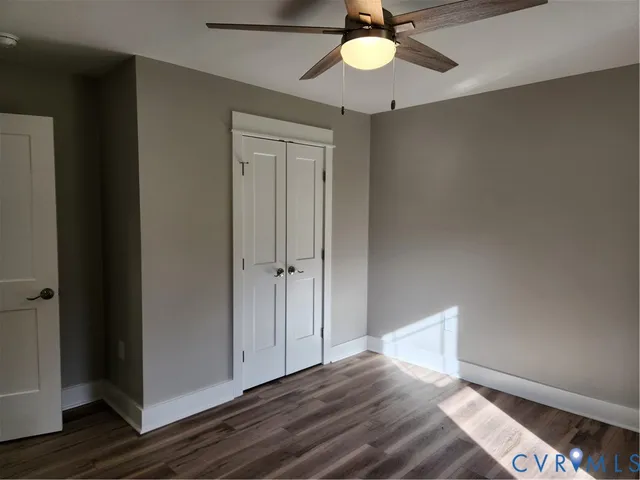 an empty room with wooden floor a ceiling fan and windows