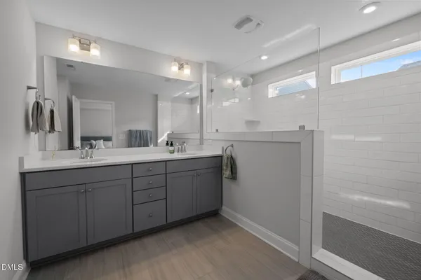 a bathroom with a double vanity sink a mirror and a shower
