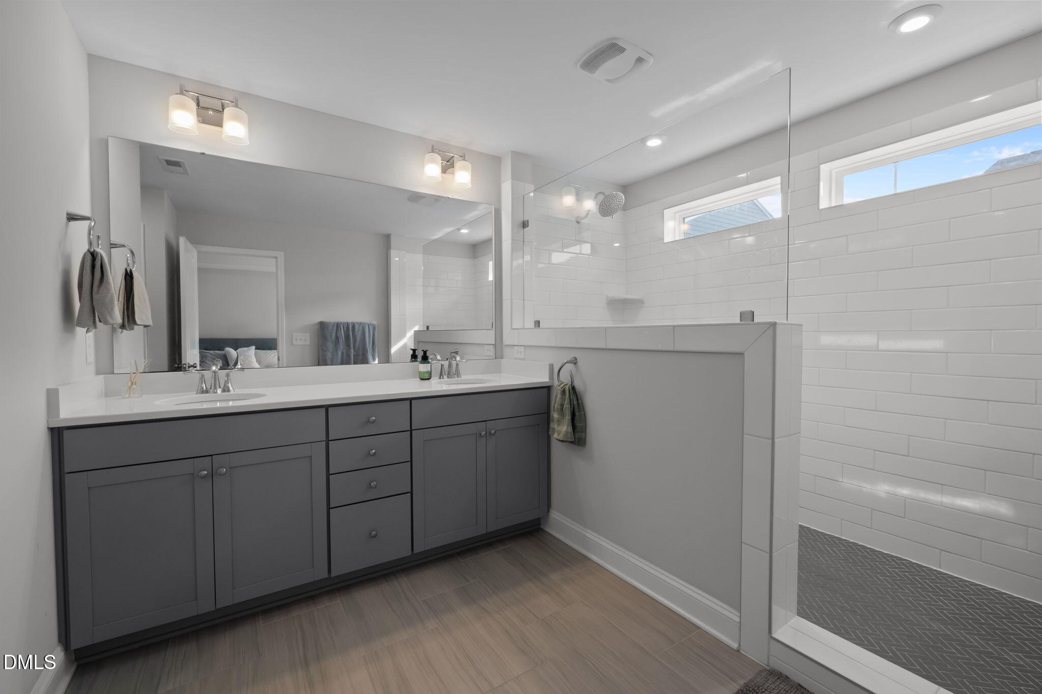 6523 Amber Springs Drive Durham, NC 27713 - Photo 17 of 32 a bathroom with a double vanity sink a mirror and a shower