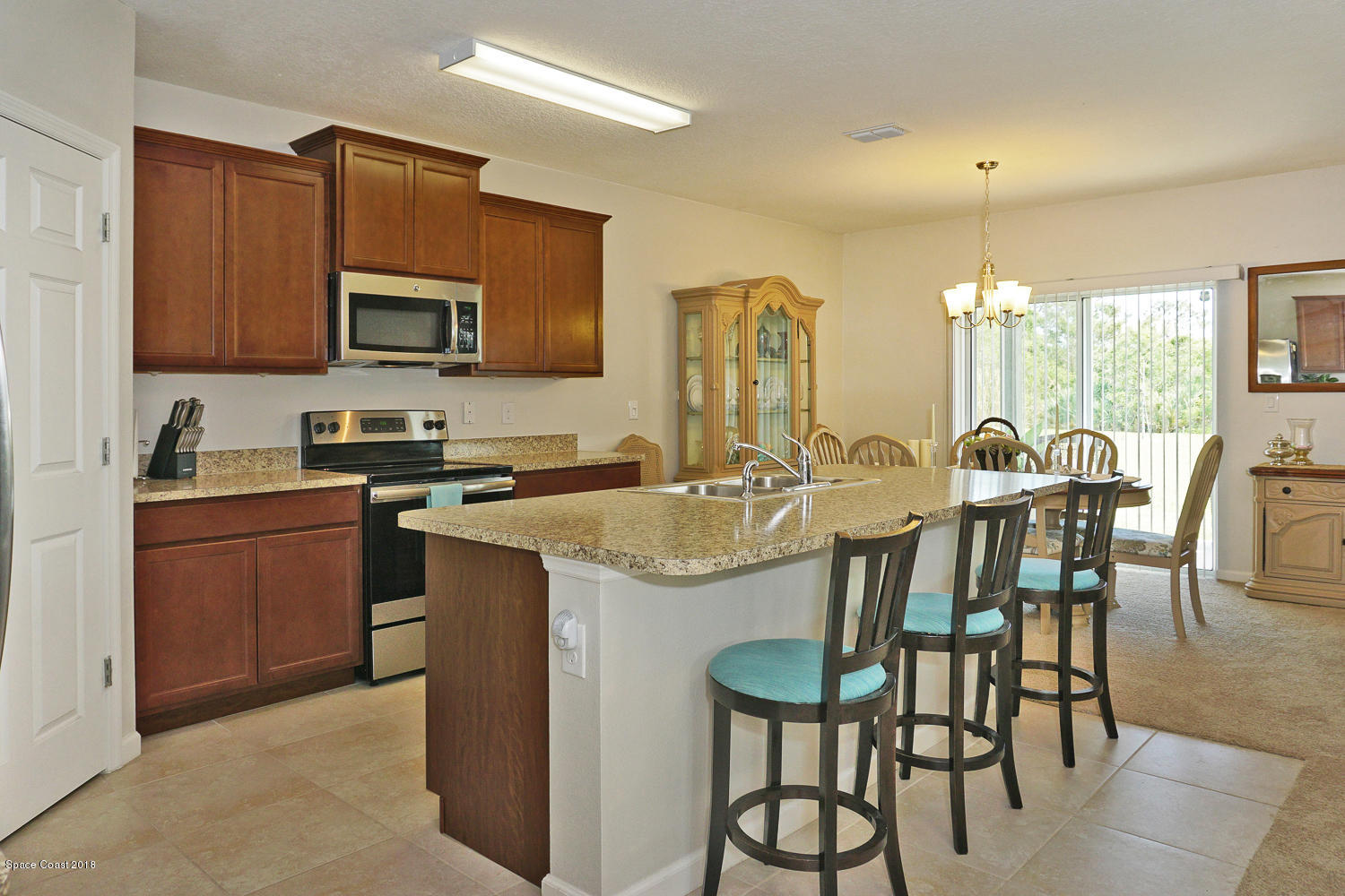 4637 Amaca Bay Lane Melbourne, FL 32935 - Photo 7 of 52 a kitchen with kitchen island granite countertop a table chairs microwave and sink