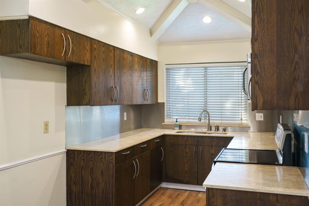 6512 Mc Cormick Ranch Court Plano, TX 75023 - Photo 18 of 40 a kitchen with wooden cabinets a sink and a stove