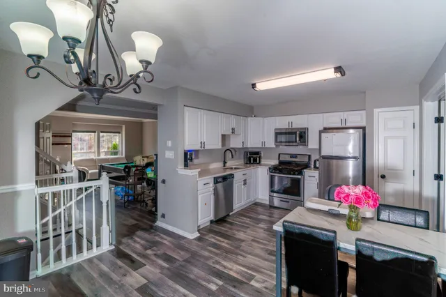 a kitchen with refrigerator a stove a dining table and chairs with wooden floor