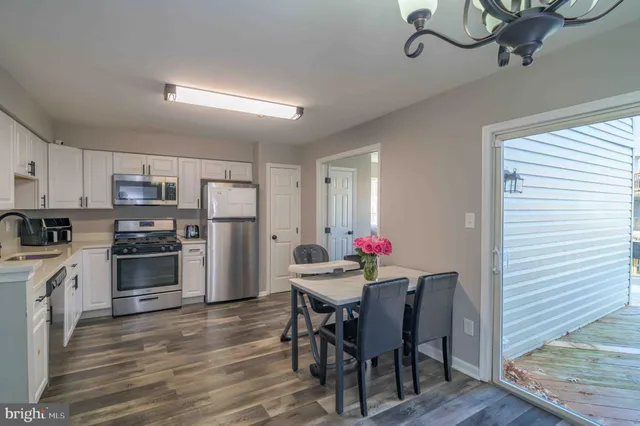 a kitchen with stainless steel appliances a dining table chairs stove and refrigerator
