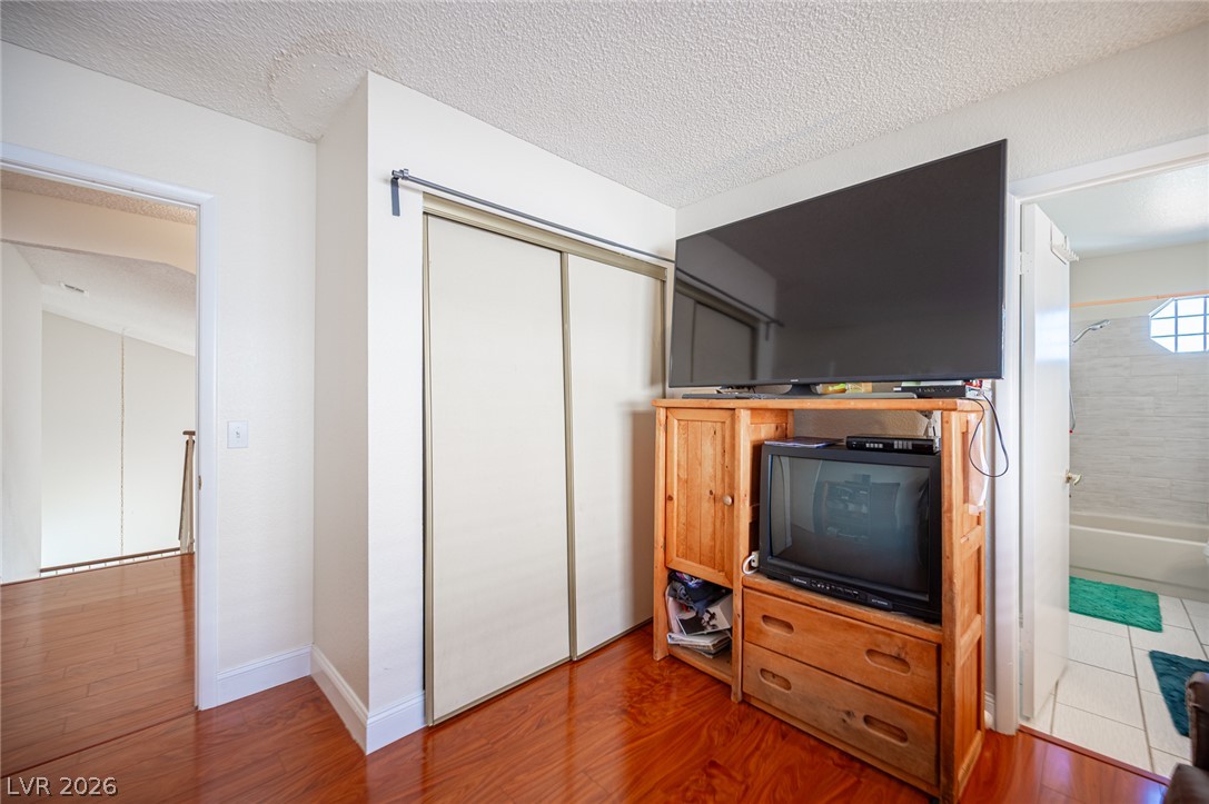 718 Rusty Spur Drive Henderson, NV 89014 - Photo 40 of 50 Rich hardwood floors complement this cozy bedroom space, offering convenient access to a private bathroom.