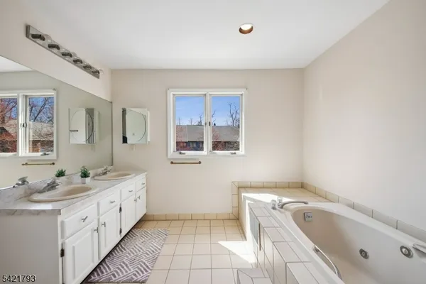 a bathroom with a tub sink and mirror