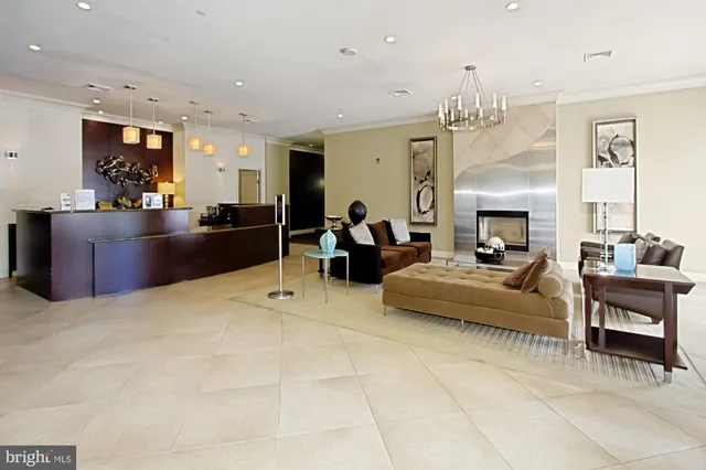 a living room with stainless steel appliances furniture a rug and a kitchen view