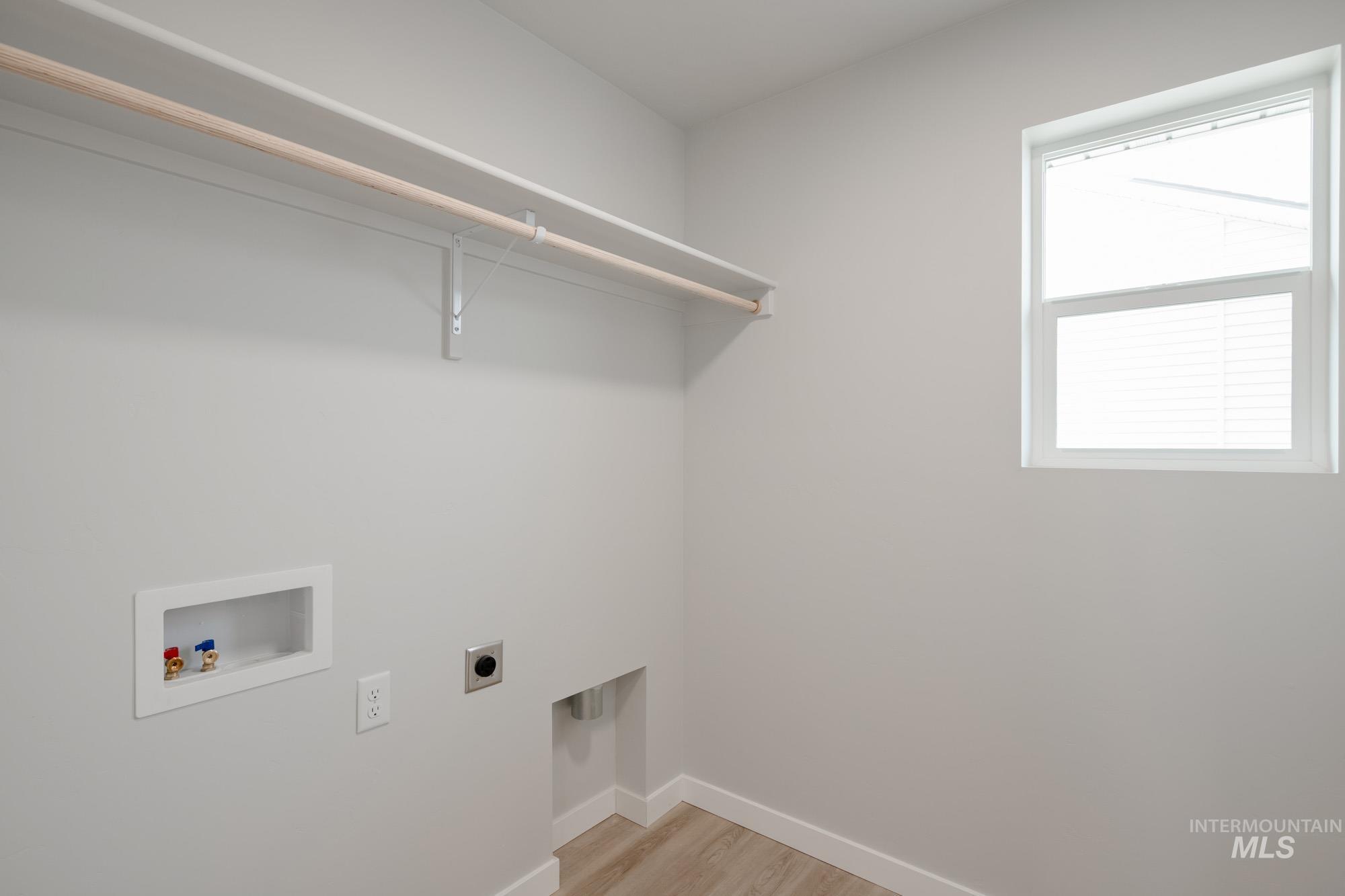 2391 West Fallon Loop Nampa, ID 83651 - Photo 13 of 20 Utility room with wood-finish flooring, a double-hung window, and a built-in shelf with a clothing rod