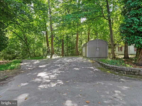 a backyard of a house with large trees and brick wall
