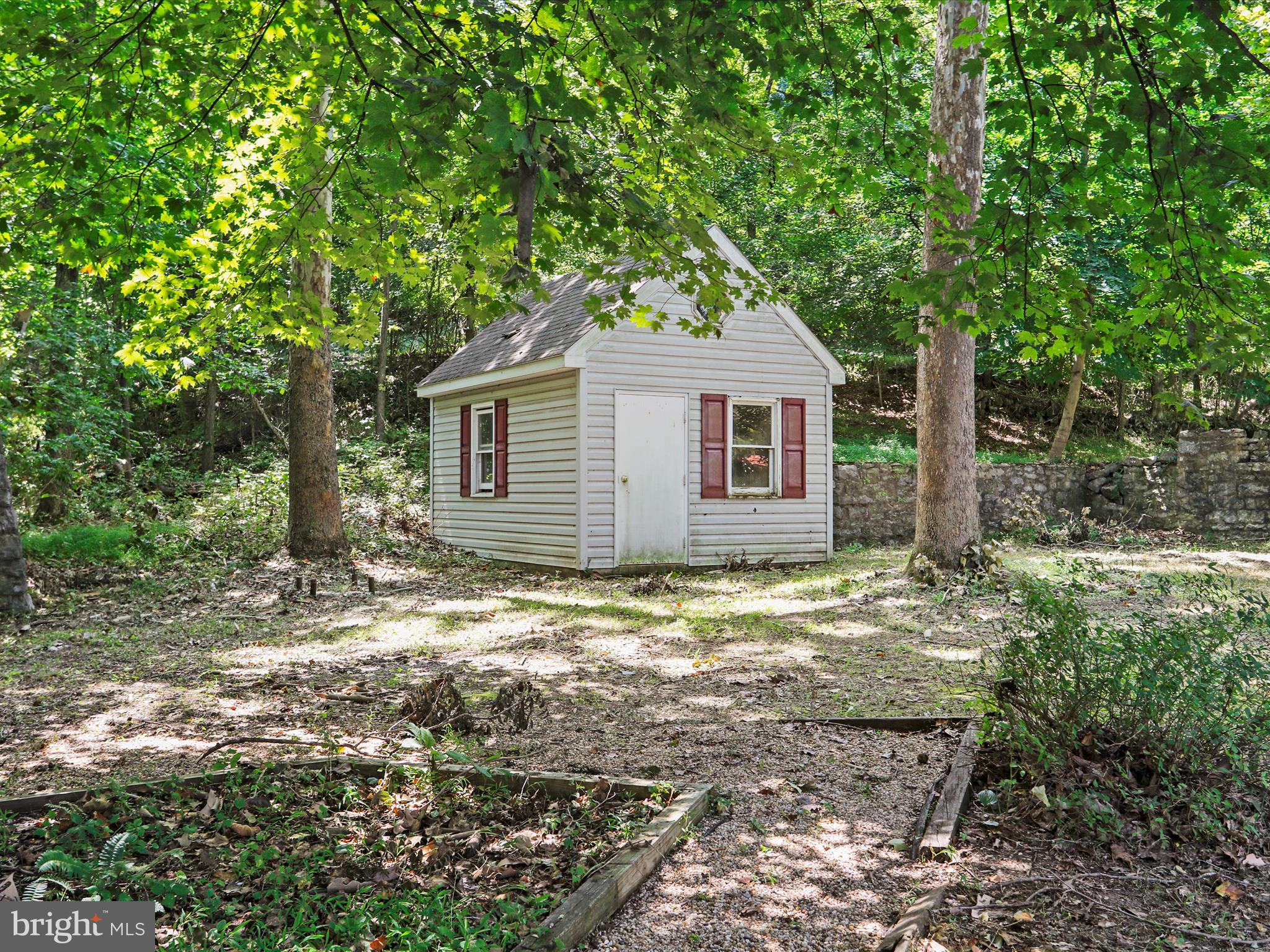 999 Aspero Lane Falling Waters, WV 25419 - Photo 10 of 57 a backyard of a house with large trees and brick wall