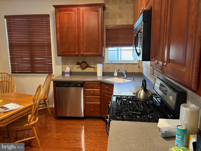 a kitchen with stainless steel appliances granite countertop a sink a stove a refrigerator a dining table and chairs