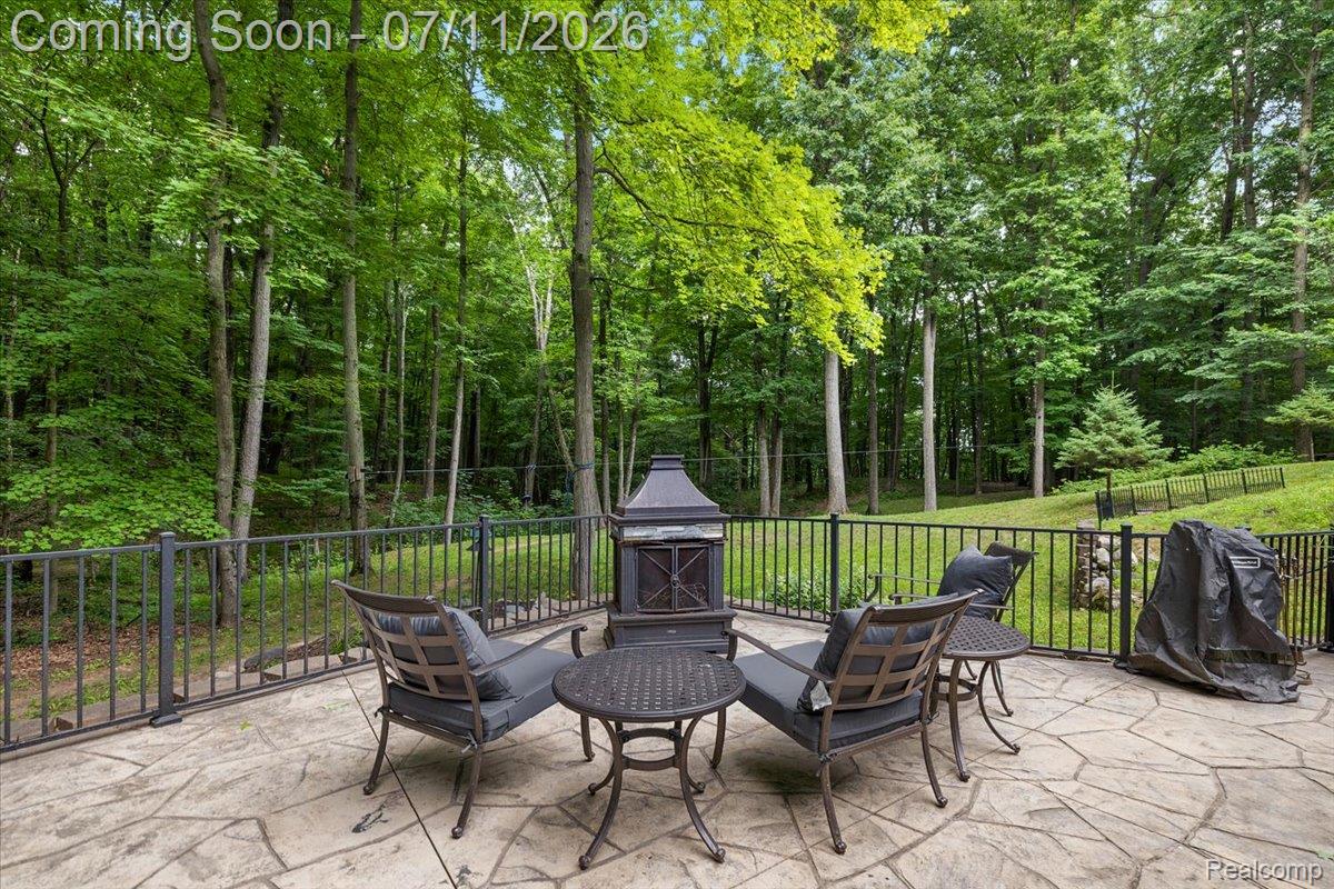 4219 Gardner Road Metamora, MI 48455 - Photo 66 of 87 Stamped concrete patio with a dark metal perimeter fence, bordered by mature trees