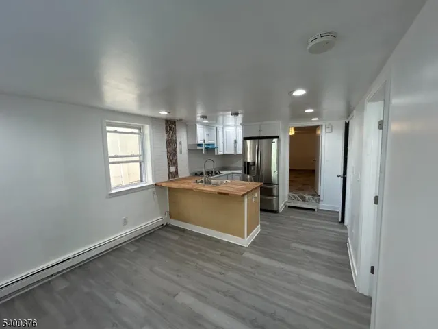 a large kitchen with a refrigerator and wooden floor