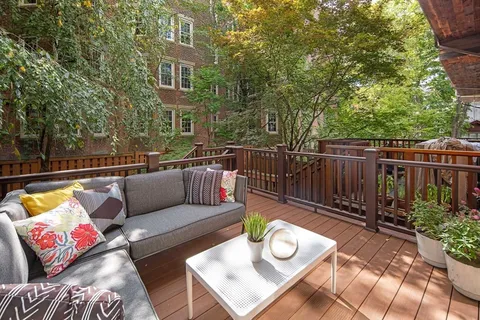a view of a deck with couches table and chairs and wooden fence