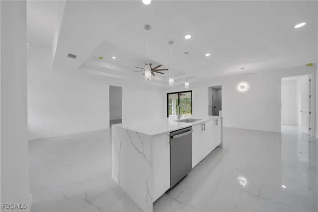 a large white kitchen with lots of counter space wooden floor and stainless steel appliances