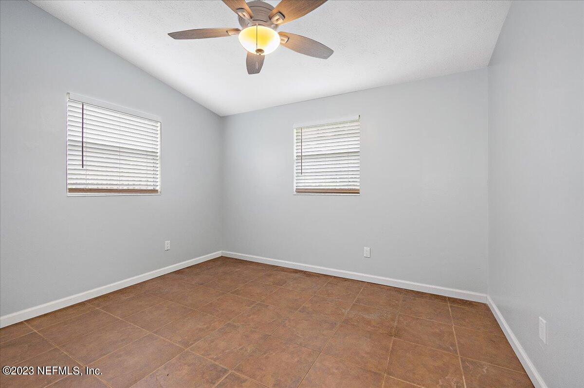 9006 Marlee Road Jacksonville, FL 32222 - Photo 6 of 18 an empty room with a chandelier fan and windows