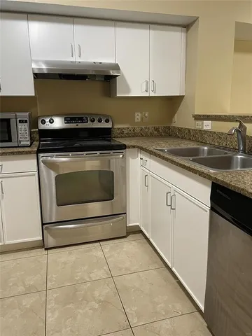 a kitchen with granite countertop a stove a sink and a microwave