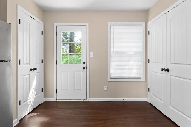 a view of an empty room with wooden floor and a window