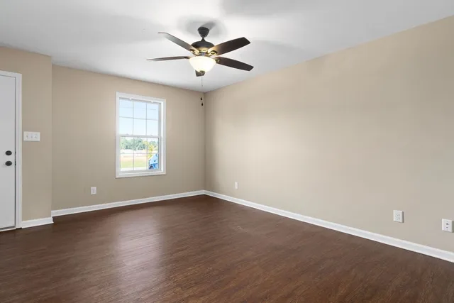 an empty room with wooden floor fan and windows