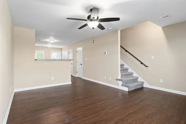 a view of an empty room with wooden floor and a ceiling fan