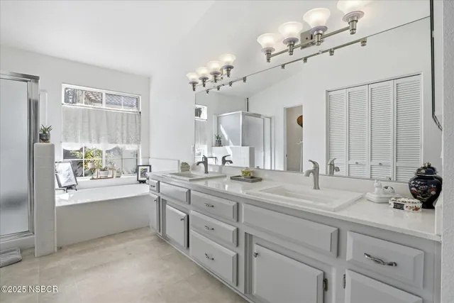 a spacious bathroom with a double vanity sink a mirror and a bathtub