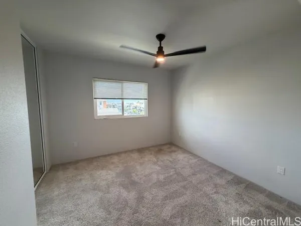 an empty room with a window and ceiling fan