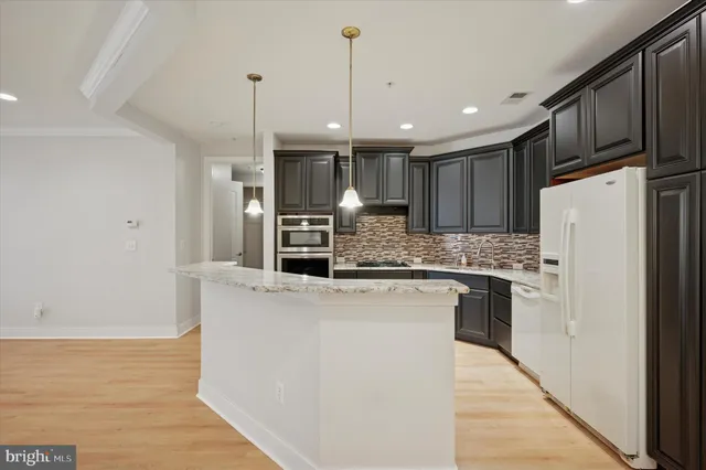 a kitchen with stainless steel appliances granite countertop a refrigerator a oven a stove and a wooden floors