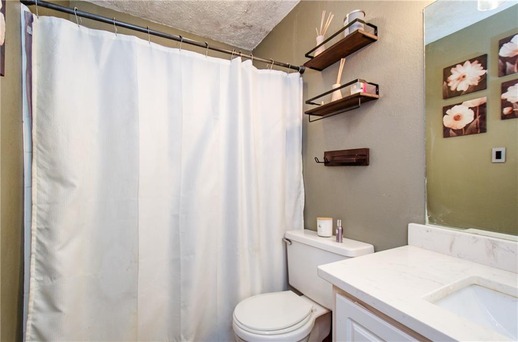 5157 Roswell Road, Unit 2 Atlanta, GA 30342 - Photo 20 of 24 a white toilet sitting next to a shower curtain