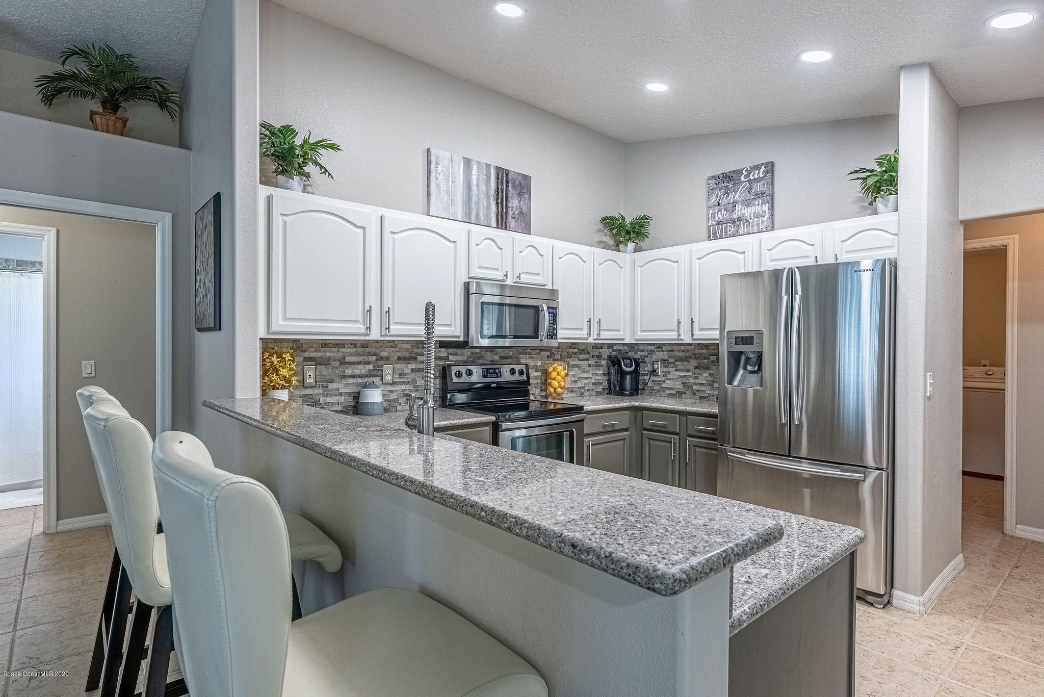 1253 Haulover Road Southwest Palm Bay, FL 32908 - Photo 26 of 52 a kitchen with white cabinets and stainless steel appliances