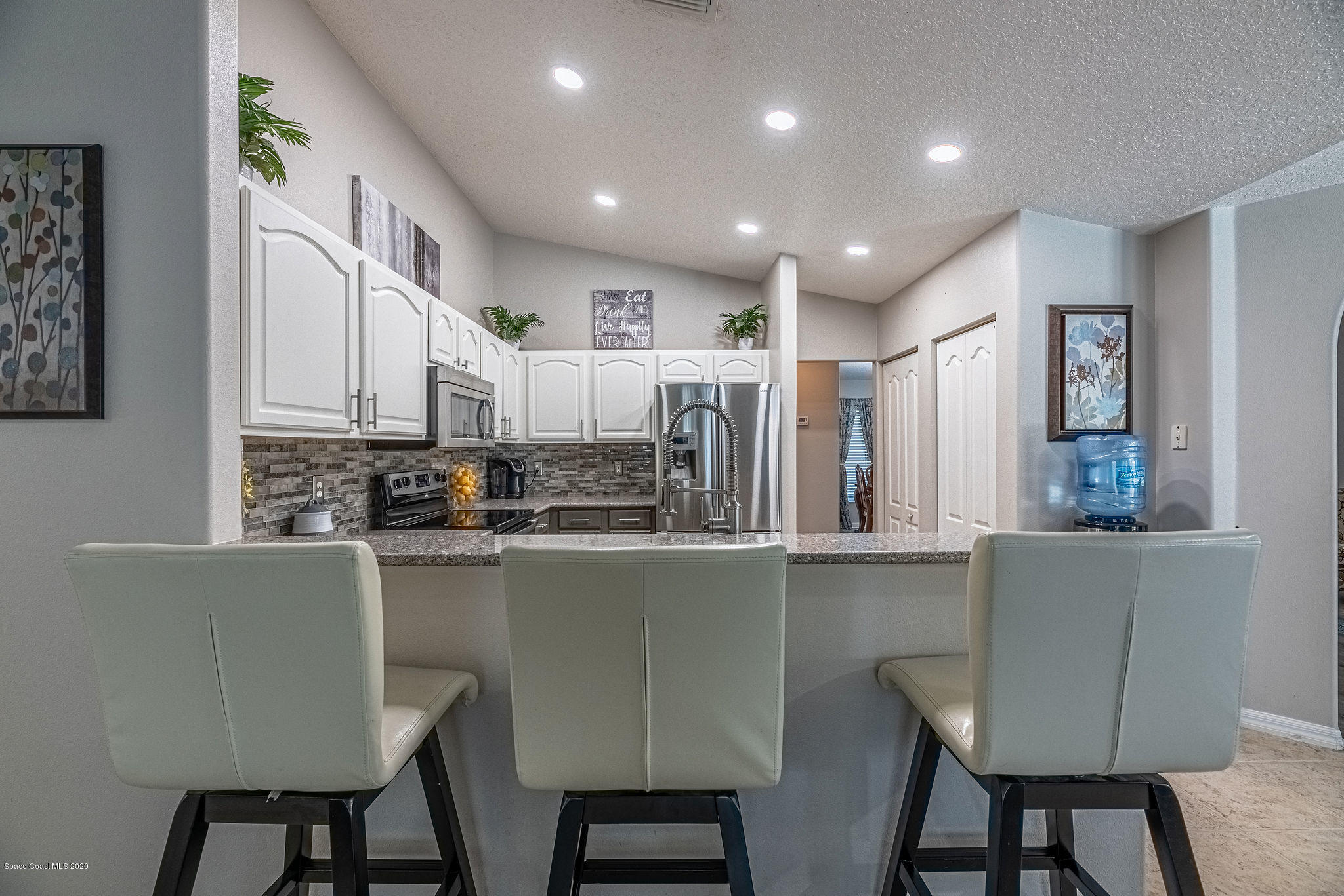 1253 Haulover Road Southwest Palm Bay, FL 32908 - Photo 27 of 52 a kitchen with stainless steel appliances granite countertop a table chairs sink and cabinets