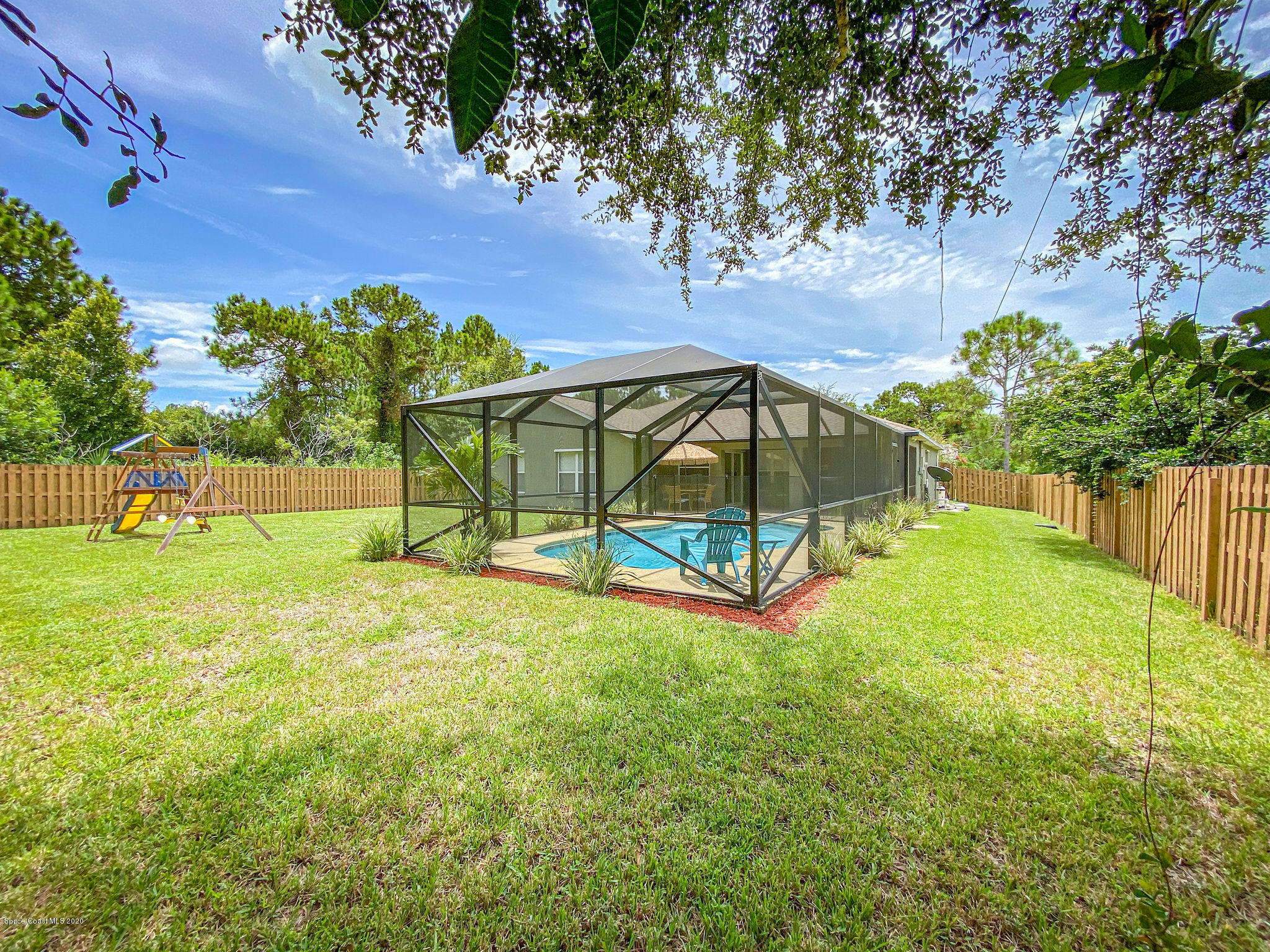 1253 Haulover Road Southwest Palm Bay, FL 32908 - Photo 9 of 52 a view of yard with swimming pool outdoor seating and trees in the background