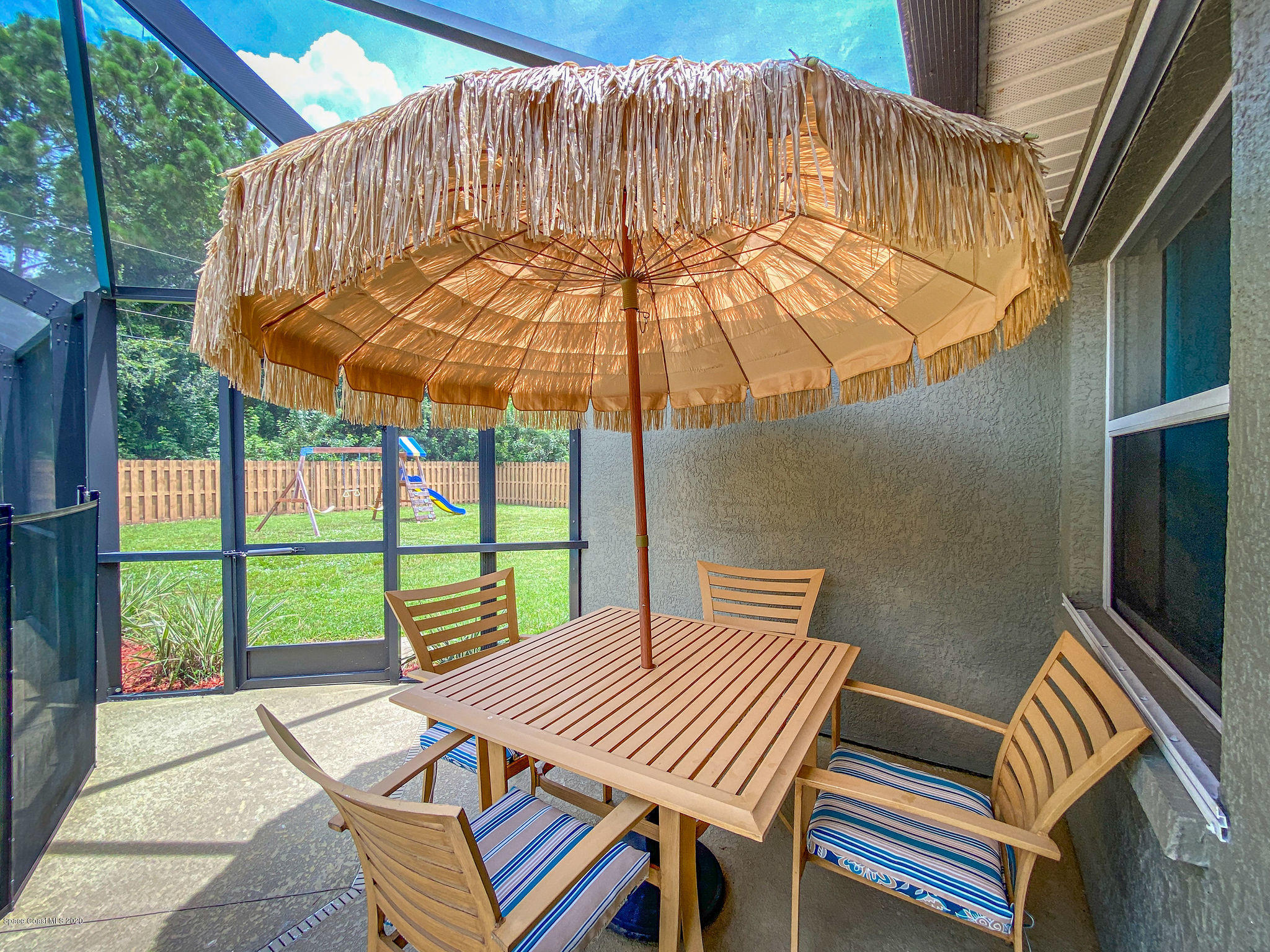 1253 Haulover Road Southwest Palm Bay, FL 32908 - Photo 10 of 52 a view of a patio with table and chairs under an umbrella with a small yard