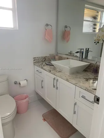 a bathroom with a granite countertop sink a toilet and a mirror