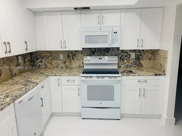 a kitchen with granite countertop white cabinets and white appliances