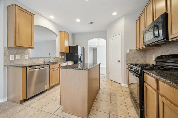 a kitchen with stainless steel appliances granite countertop a stove a sink and a refrigerator