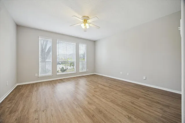 an empty room with wooden floor and windows