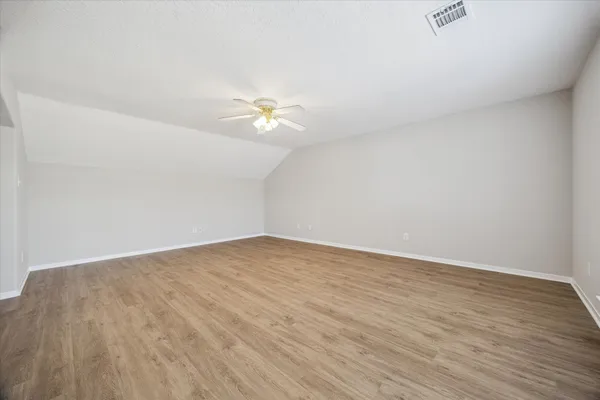 an empty room with wooden floor and fan
