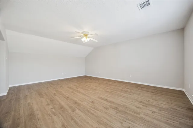 an empty room with wooden floor and fan