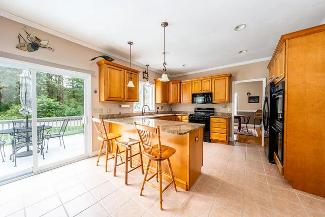 a kitchen with stainless steel appliances kitchen island granite countertop a refrigerator a stove top oven and a sink with granite countertops